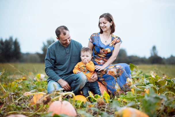 Mladá rodina, máma, táta a malý chlapec tráví čas na dýňové farmě. Čas na pád. Americké svátky - Halloween a Den díkůvzdání - Fotografie, Obrázek