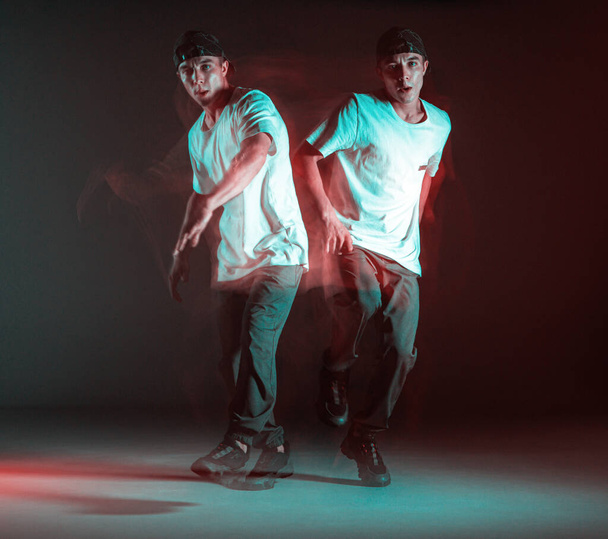 Stylish young boy breakdancer rapper dancing hip-hop in neon light. Long exposure shot - Фото, зображення