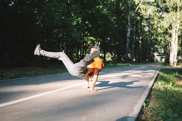 Cool young guy dancing breakdance on the road in the park in summertime. Breakdancing school poster - Fotó, kép