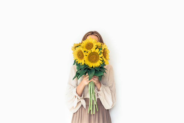 Krásná mladá žena v lněných šatech drží slunečnice kytice. - Fotografie, Obrázek