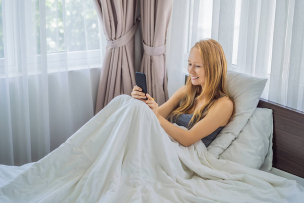 Donna che parla tramite videochiamata mentre si trova a letto - Foto, immagini