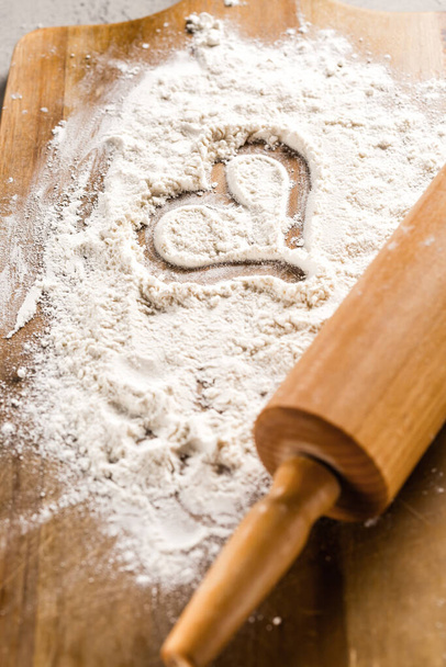 Rodillo con forma de corazón en harina sobre tabla de cortar de madera. Amor concepto de hornear  - Foto, imagen