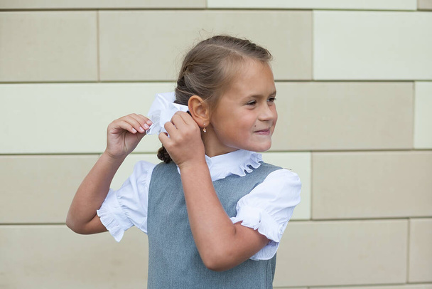 schattig klein meisje past haar haar aan. boog met een zeis. Eerste klasser. dag van kennis. - Foto, afbeelding