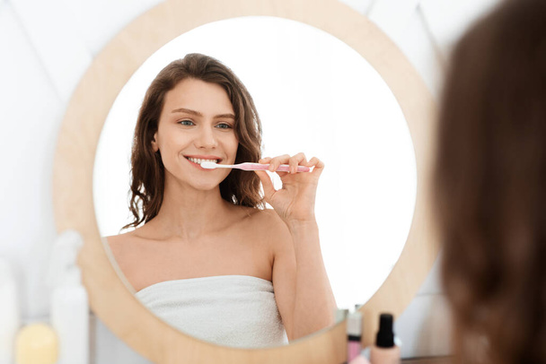 Feliz joven mujer cepillarse los dientes en el baño - Foto, imagen