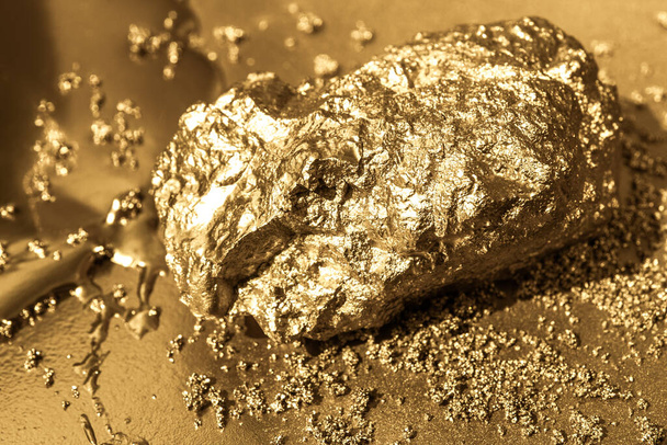 Gold stone on a gold background. Liquid gold and gold dust. - Photo, Image