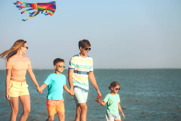 Happy family flying kite on sea beach at resort - Photo, Image