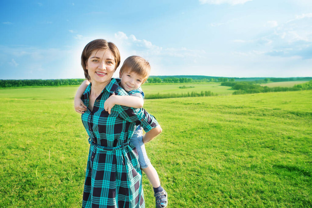 Mother and son having fun on green field - Foto, imagen