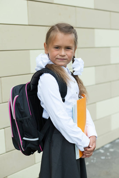 Mała dziewczynka z dwoma warkoczami i plecakiem idzie do szkoły. 1 września. Edukacja - Zdjęcie, obraz
