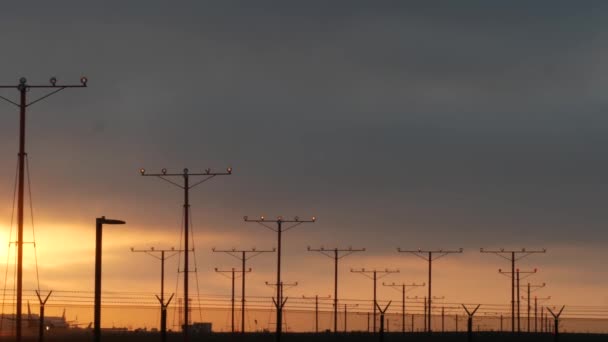 ロサンゼルス、カリフォルニア州の日没時にLAX空港に飛行機の着陸。旅客便や貨物飛行機のシルエット、劇的な雲。飛行場への航空機到着。国際輸送機 - 映像、動画