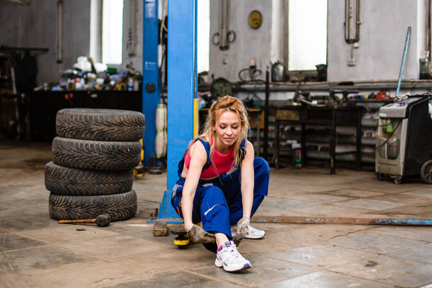 Egy lány egy autószervizben gumikkal dolgozik. - Fotó, kép