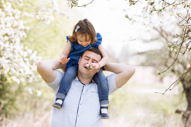 Отец играет со своей дочерью в парке. Дочь сидит на плечах отца. Портрет счастливой семьи. father 's, baby' s day - Фото, изображение