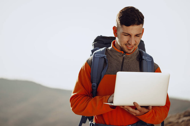 Young man backpacker using his laptop in mountain journey - Foto, Imagem