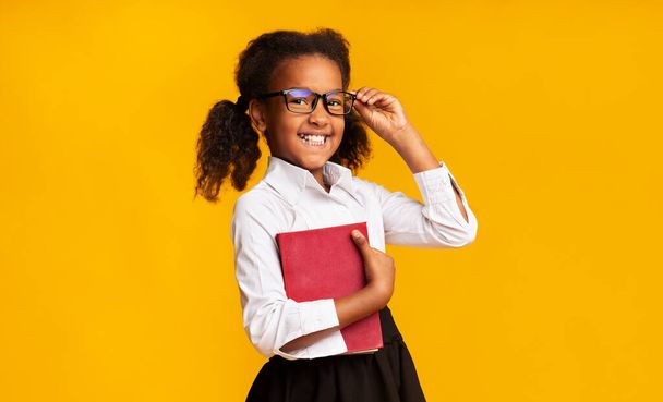 Cheerful Schoolgirl Holding Book Smiling To Camera Standing In Studio - Valokuva, kuva