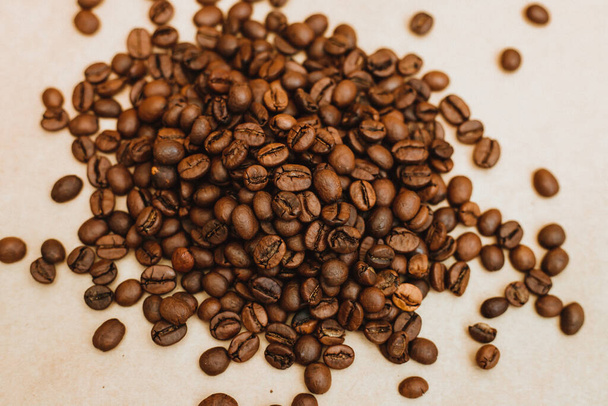Coffee bean background. Dark-colored roasted coffee beans scattered on Kraft paper. Texture. - Foto, Bild