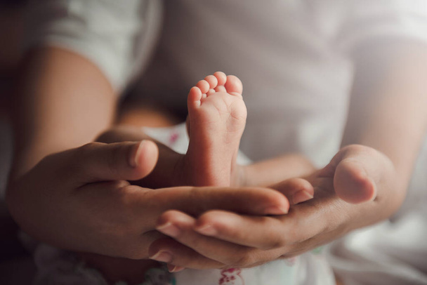 Padres sosteniendo en las manos los pies del bebé recién nacido. - Foto, imagen