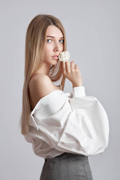 Blonde beauty woman holds white flower in hand. Beautiful soft hands and soft skin. Cosmetics for beauty hand care - Valokuva, kuva