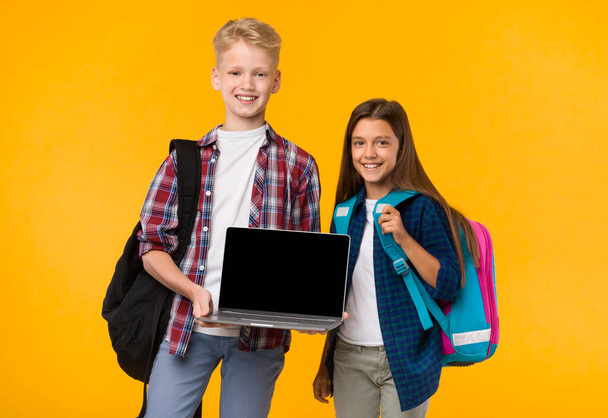 School jongen en meisje tonen laptop scherm op camera - Foto, afbeelding