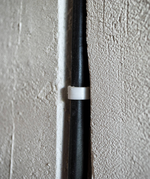 recess in the wall for the wire during repairs in the apartment. black electrical wire. wall chase - 写真・画像