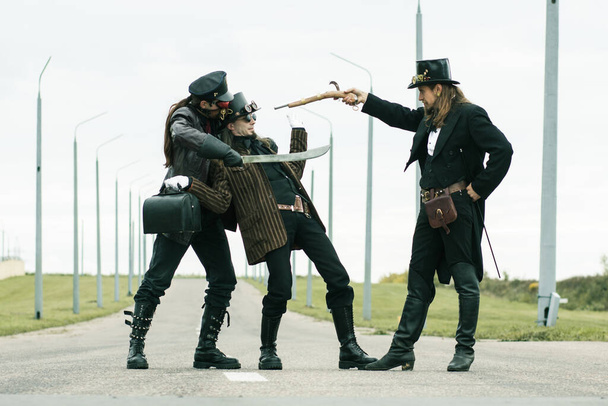 Three mans in steampunk style stage a robbery on the road - Photo, image