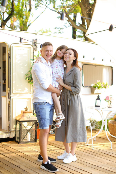 Father and mother holding daughter near house on wheels. - 写真・画像
