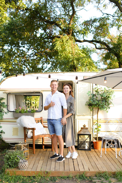Portrait of happy husband and wife standing near house on wheels. - 写真・画像
