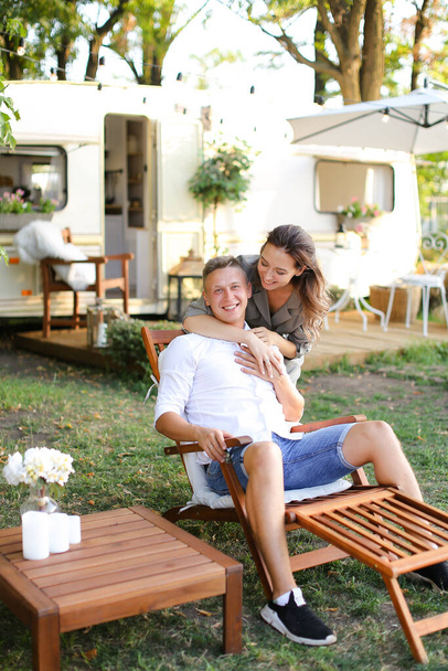 Σύζυγος και σύζυγος κάθονται σε καρέκλα κοντά στο σπίτι με ρόδες. - Φωτογραφία, εικόνα