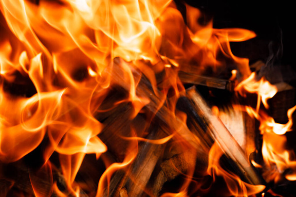 Tüzes láng textúrája fekete háttérrel. égő tűz a kályha közelkép - Fotó, kép