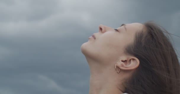 Close up portrait of female face looking up into stormy sky copy text space. Detailed macro side view of woman with closed eyes on nature rainy background slow motion. Facial care cosmetics products - Footage, Video