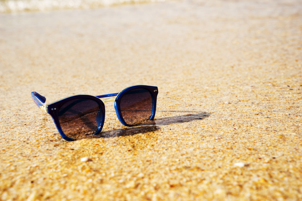 lunettes de soleil femme sur le sable sur fond de mer, un accessoire du soleil - Photo, image