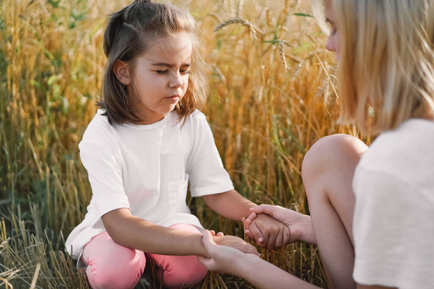 Девочки молятся и держатся за руки на пшеничном поле. Молитесь друг за друга, поддерживайте друг друга - Фото, изображение