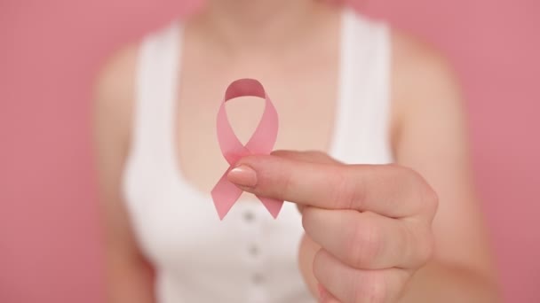 Zblízka, žena držící hedvábně růžovou stuhu mezi prsty. Měsíc povědomí o rakovině prsu růžový říjen - Záběry, video