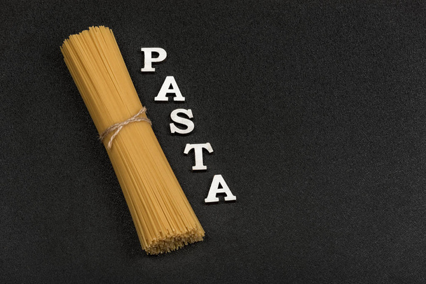 Uncooked spaghetti on gray background. Classic Italian spaghetti. Pasta background. - 写真・画像