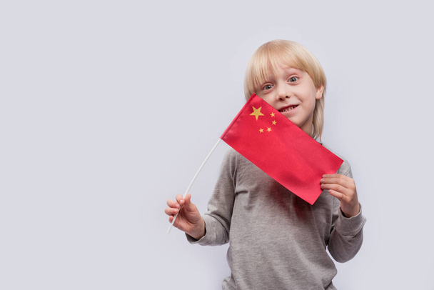 Aranyos, szőke fiú Kína zászlajával. A gyermekek oktatása Kínában. - Fotó, kép