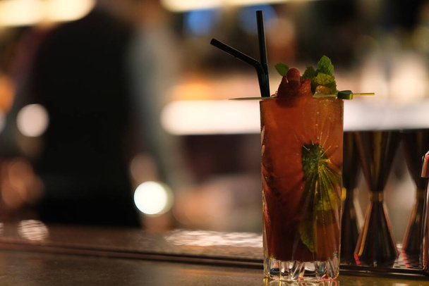 Sluit een glas cocktail af op de bar. gedeconcentreerde barman met kleurrijke bokeh - Foto, afbeelding