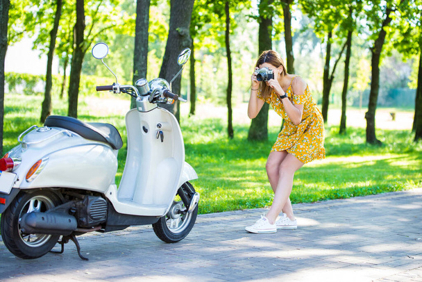 krásná evropská dívka ve žlutých šatech s retro skútrem v ranním parku - Fotografie, Obrázek