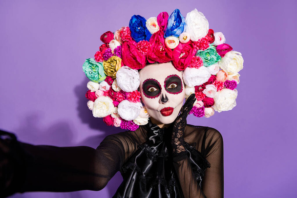 Closeup photo of funny traditional folklore witch death day facial creepy scary makeup mask masquerade latin holiday make take selfies wear floral headwear costume isolated violet background - 写真・画像