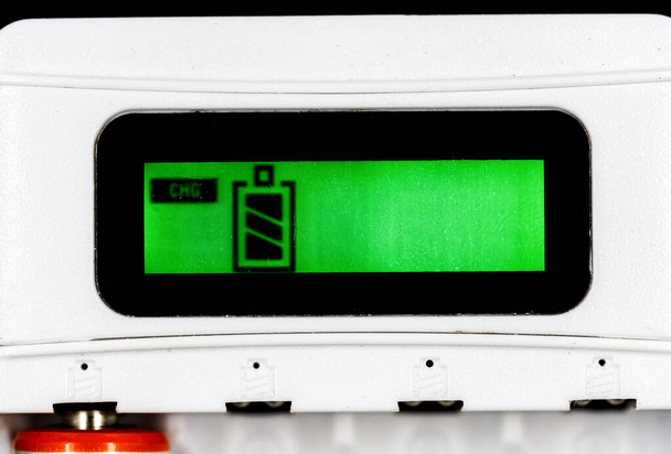 Proces ładowania akumulatora. Zielony ekran ze wskaźnikiem baterii. ładowarka akumulatora Close Up - Zdjęcie, obraz