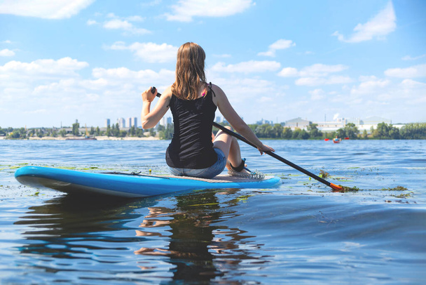 Krásná žena se zabývá v létě aktivní sporty na řece na SUP palubě. - Fotografie, Obrázek