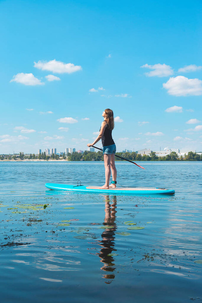 Schöne Millennial-Frau auf einem SUP-Board auf dem Fluss. Aktives Ruhekonzept.  - Foto, Bild
