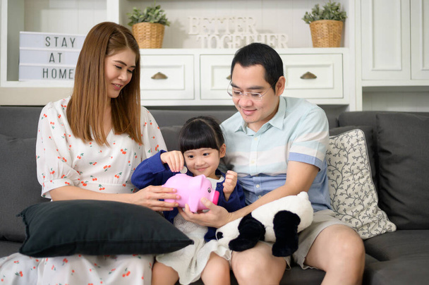 An asian family is teaching daughter on savings money with a piggy bank, financial planning concept - 写真・画像