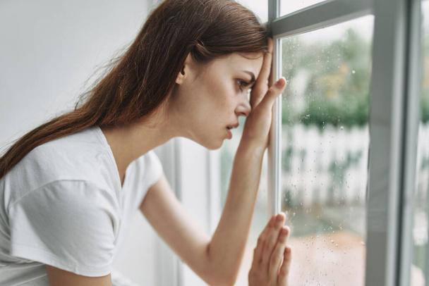 Θλιβερή γυναίκα κοιτάζει έξω από τα παράθυρα εσωτερική μοναξιά  - Φωτογραφία, εικόνα