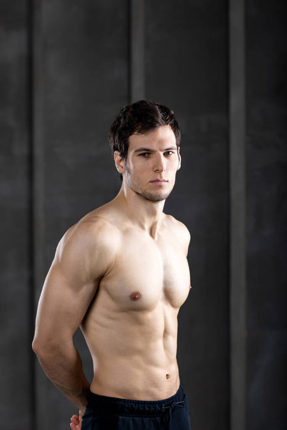 Muscle sexy young man shirtless. Strong bodybuilder on dark. - Fotoğraf, Görsel