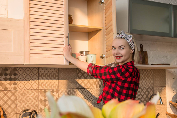 Beautiful woman in the image of pin up opening the drawer door in the kitchen. - Fotografie, Obrázek