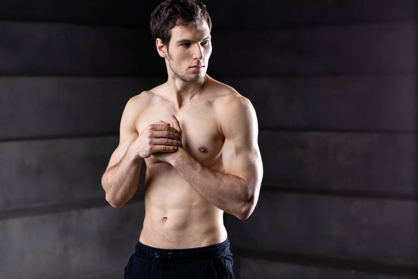 Muscular man shirtless. Strong bodybuilder on dark. - Foto, Imagen