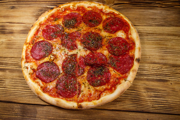 Pyszna świeża pizza z kiełbasą i serem na drewnianym stole - Zdjęcie, obraz