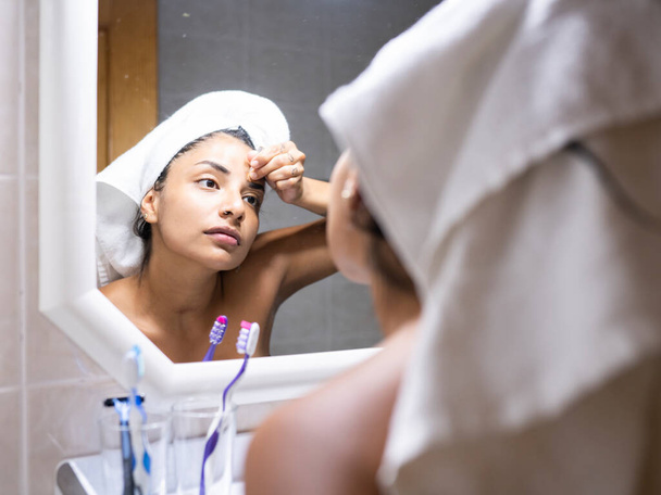 πετσέτα γυναίκα στο κεφάλι βάζοντας μακιγιάζ στον καθρέφτη - Φωτογραφία, εικόνα