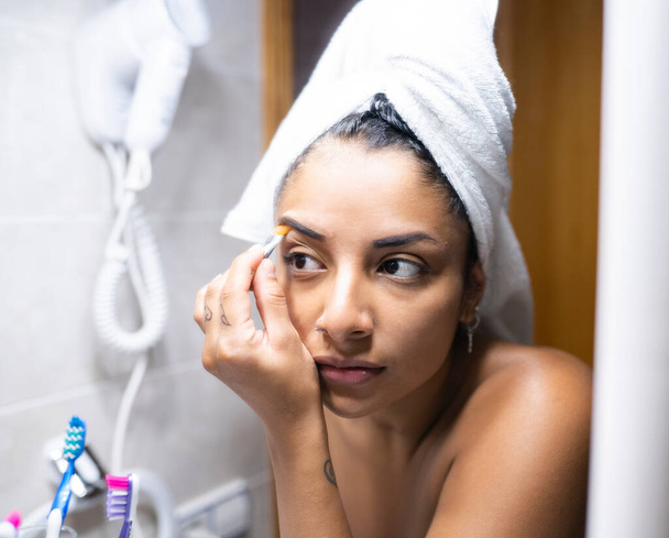 donna con asciugamano in capelli che si trucca davanti allo specchio - Foto, immagini
