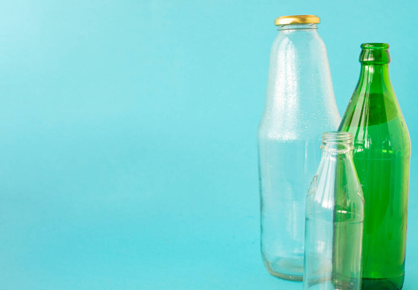 Empty glass transparent and green bottles on a blue background. A copy of the space. Ecology and Zero waste concept. - Foto, afbeelding