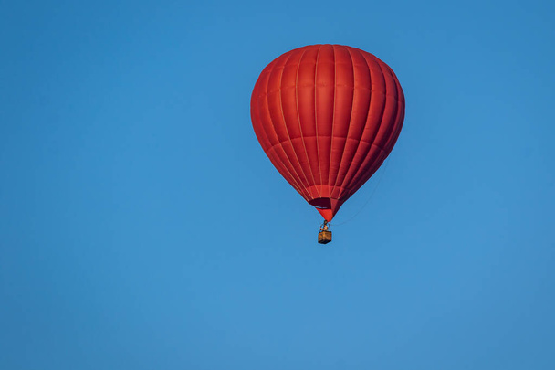 Balão de ar quente vermelho brilhante em voo contra um fundo de céu azul. Balão de pintura aquarela colorido voando alto. Close-up. - Foto, Imagem