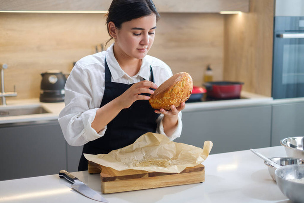 Aantrekkelijke Baker Meisjes checkt brood voor paraatheid. - Foto, afbeelding